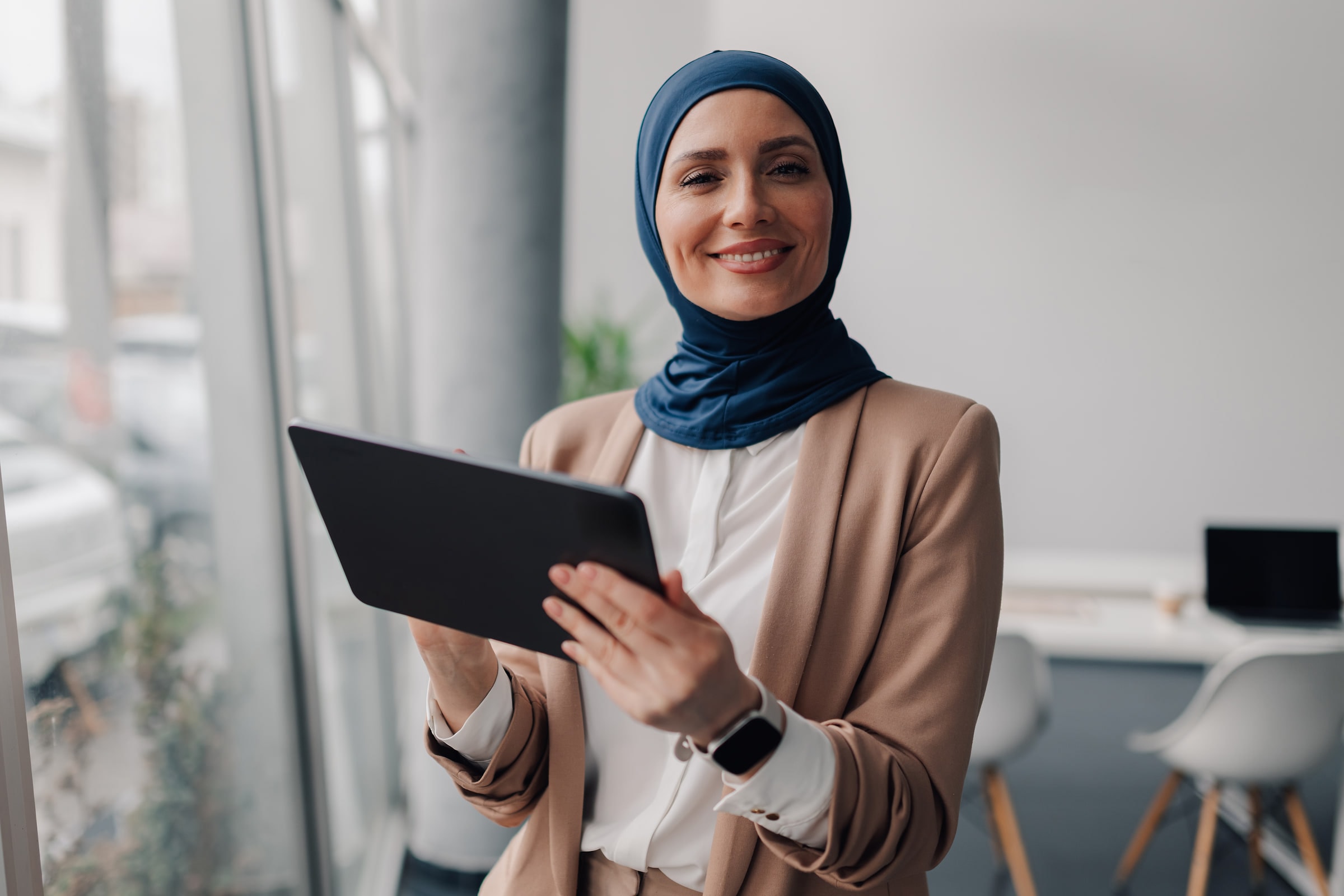 موظفة مبتسمة تحمل جهازًا لوحيًا
